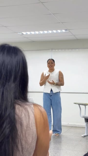 Quezia Machado em pé, falando para uma turma em sala de aula.